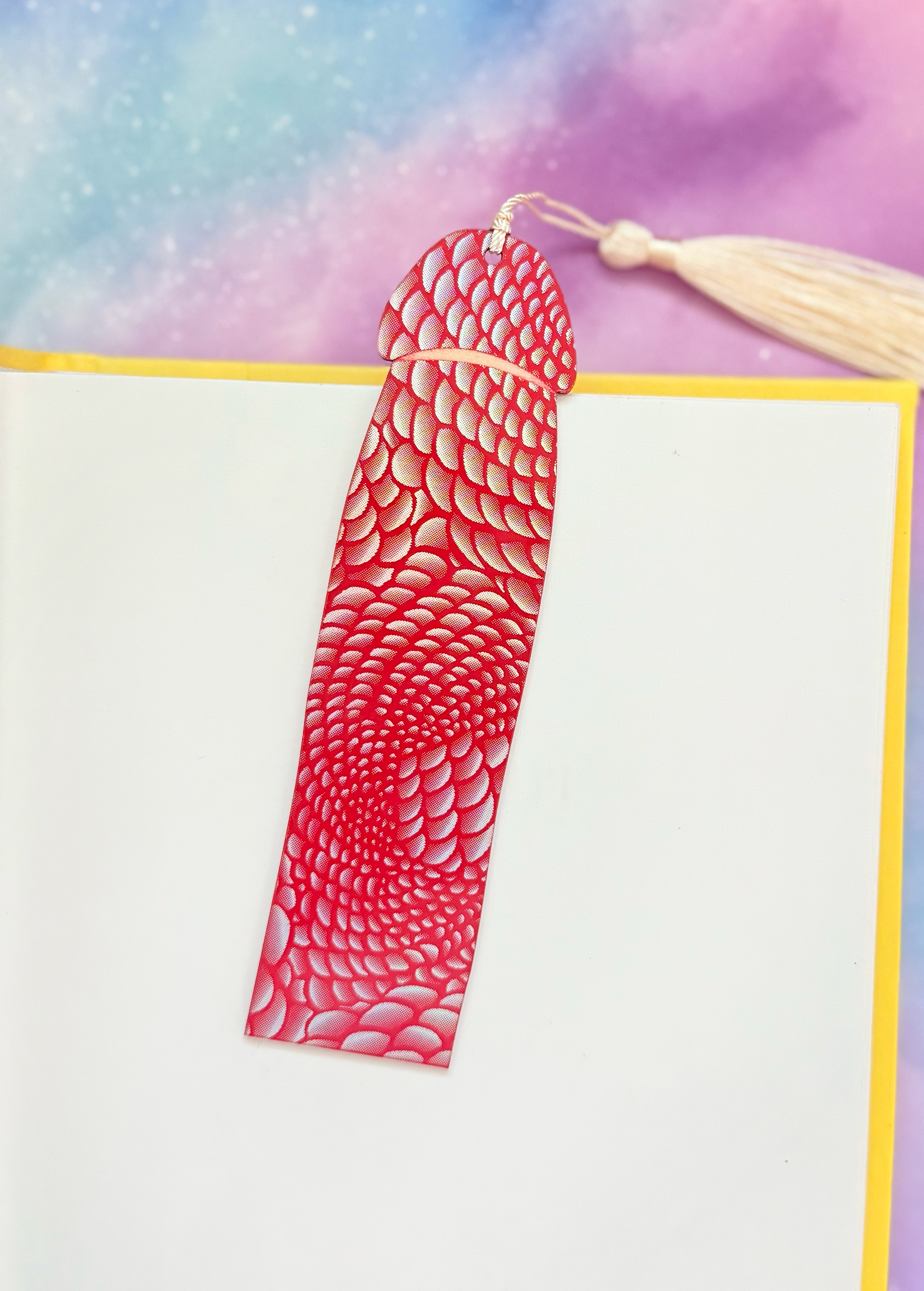 Red textured bookmark with tassel on a colorful watercolor background