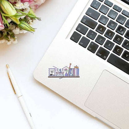 Laptop with a sticker on a desk with flowers and a pen