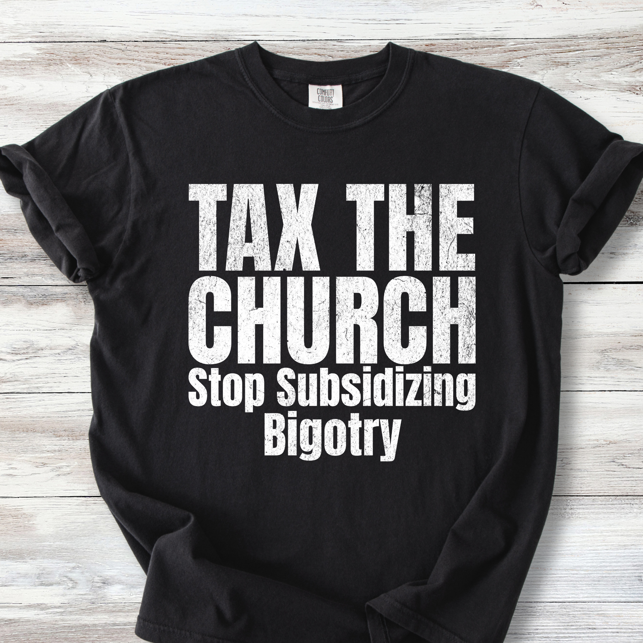  A Comfort Colors Tee with the words TAX THE CHURCH Stop Subsidizing Bigotry.  Available colors are black and denim with white lettering &amp; Ivory and Mustard with brown lettering. Lettering is bold with a bit of grunge.  