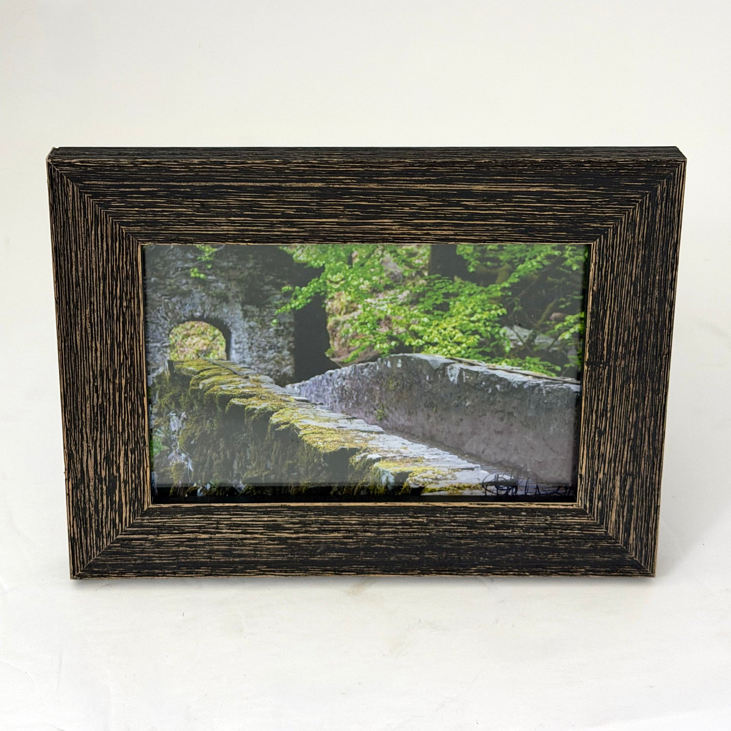 framed print of a stone bridge in a forest in the scottish highlands in a weathered style brown frame