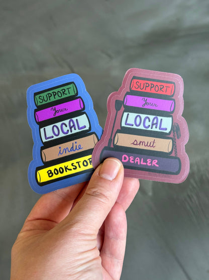 Two colorful stickers held by a hand with a gray background
