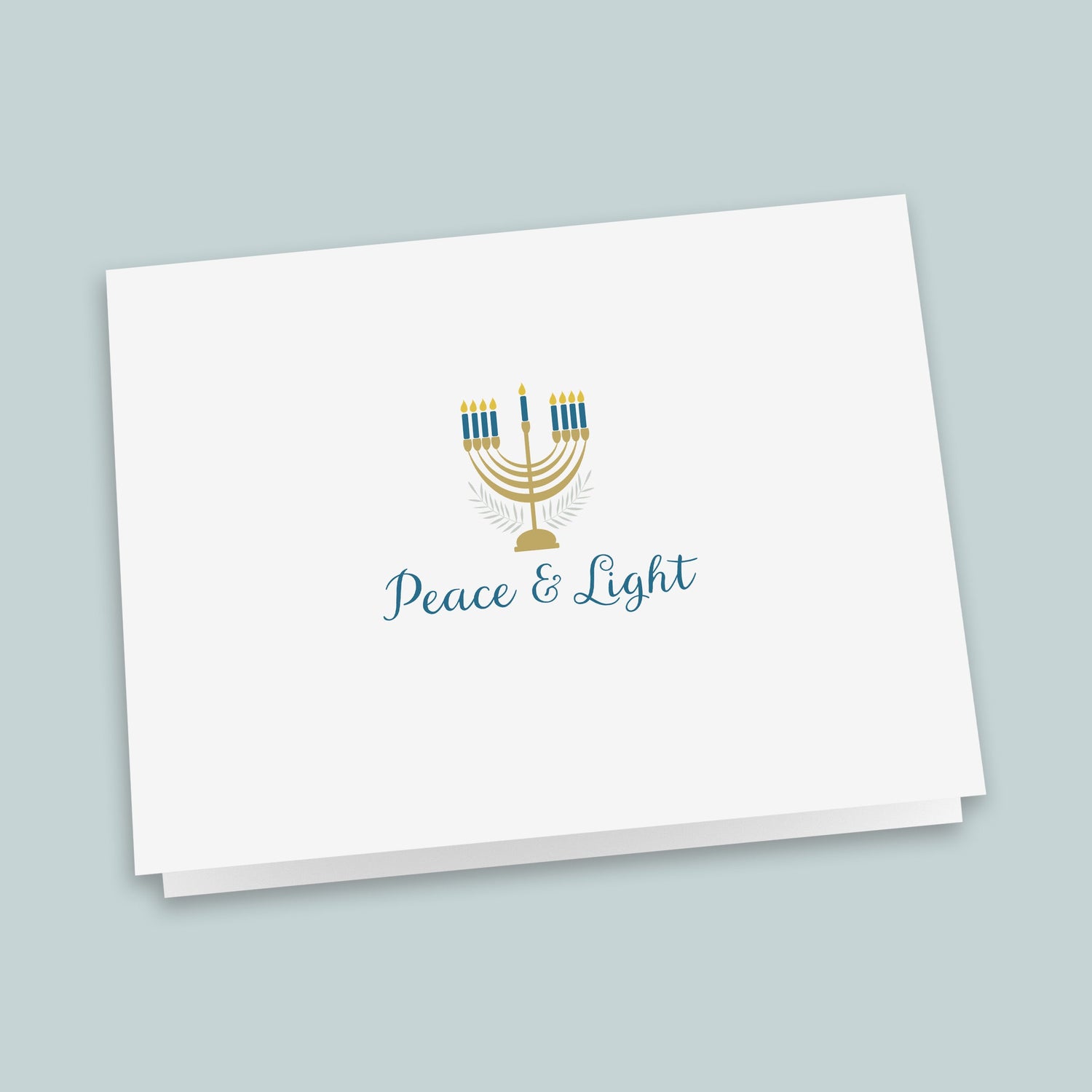 A white greeting card with a stylized graphic of a menorah and the text "Peace &amp; Light" printed on it.