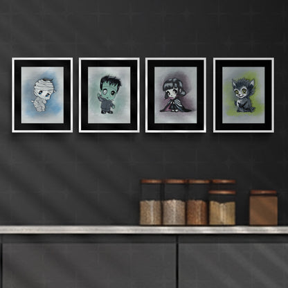 Set of four monster art prints in white frames with black mats, hung in a row on a charcoal kitchen wall above canisters of dry goods.