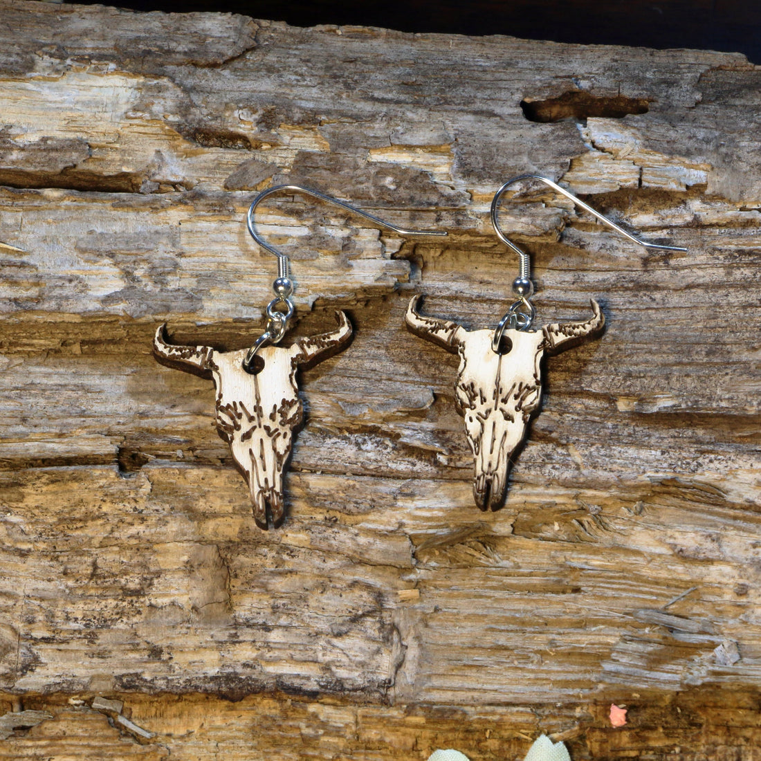 Hand-painted wooden longhorn cattle skull dangle earrings featuring a detailed western cow skull with curved horns inspired by the American Southwest. Crafted from lightweight wood with hypoallergenic .925 sterling silver hooks, these rustic earrings are perfect for western fashion, rodeo fans, ranch life, cowgirl style, country music festivals, Texas pride, and anyone who loves southwestern-inspired jewelry.