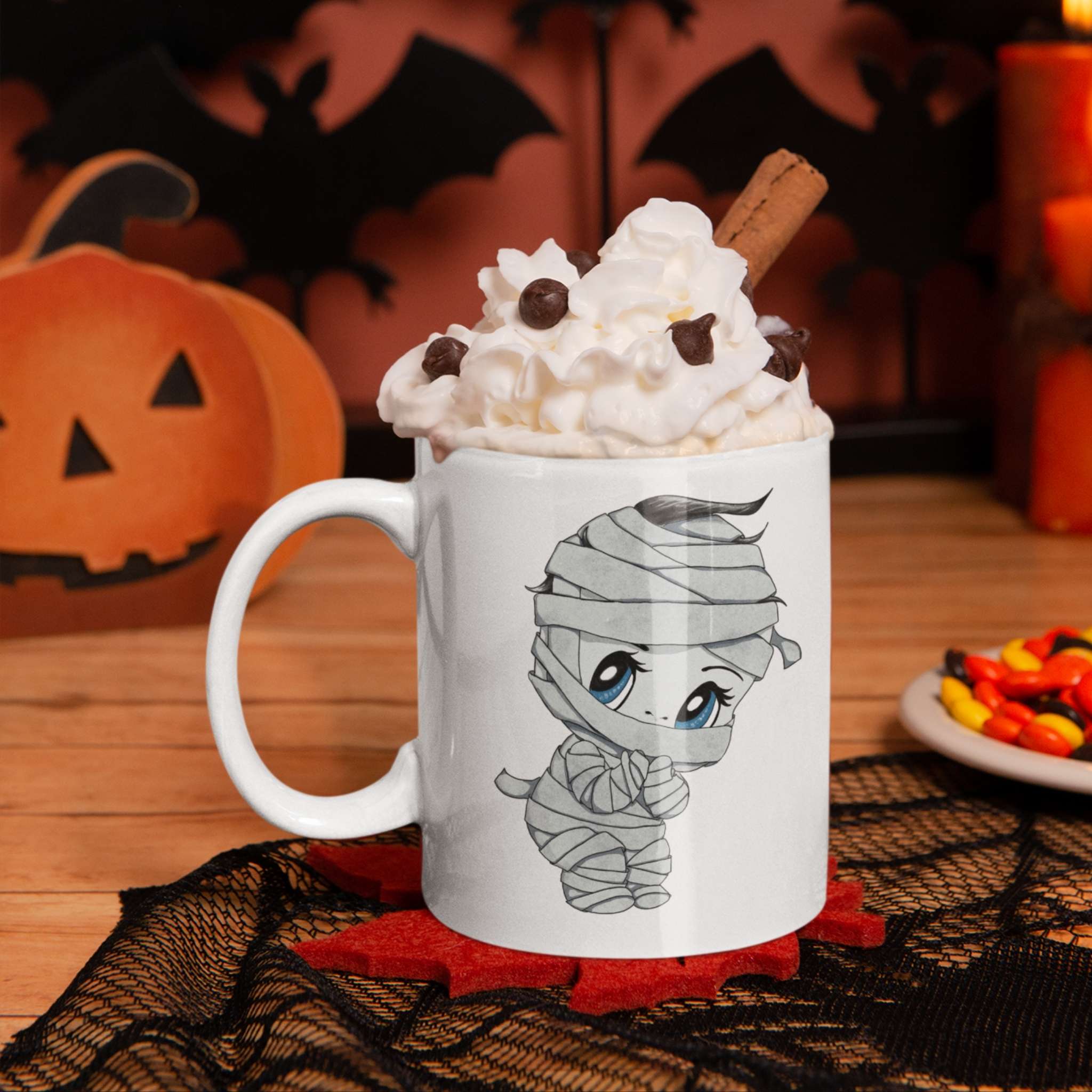 Cute mummy mug with whipped cream and cinnamon on a Halloween table with pumpkin and bats