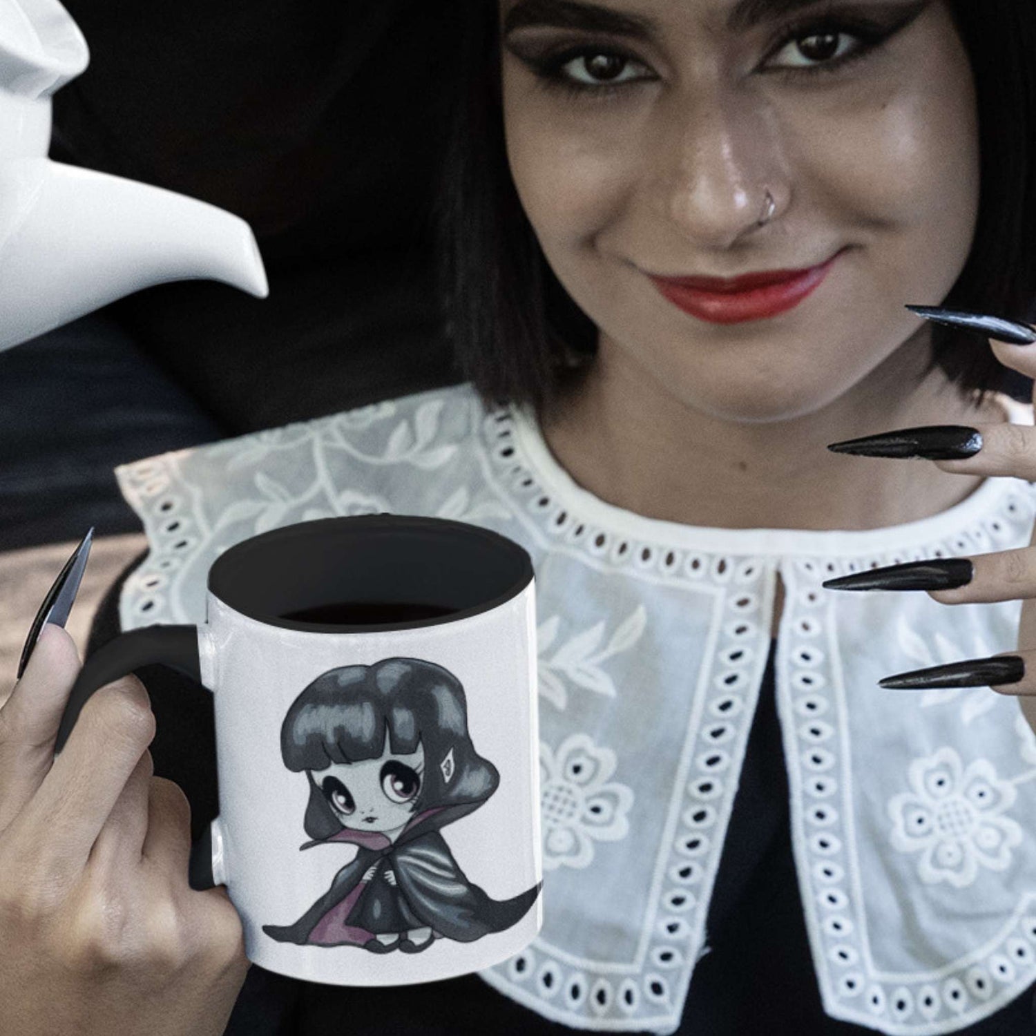 Woman with red lips and black nails holding the cute vampire coffee mug filled with black coffee