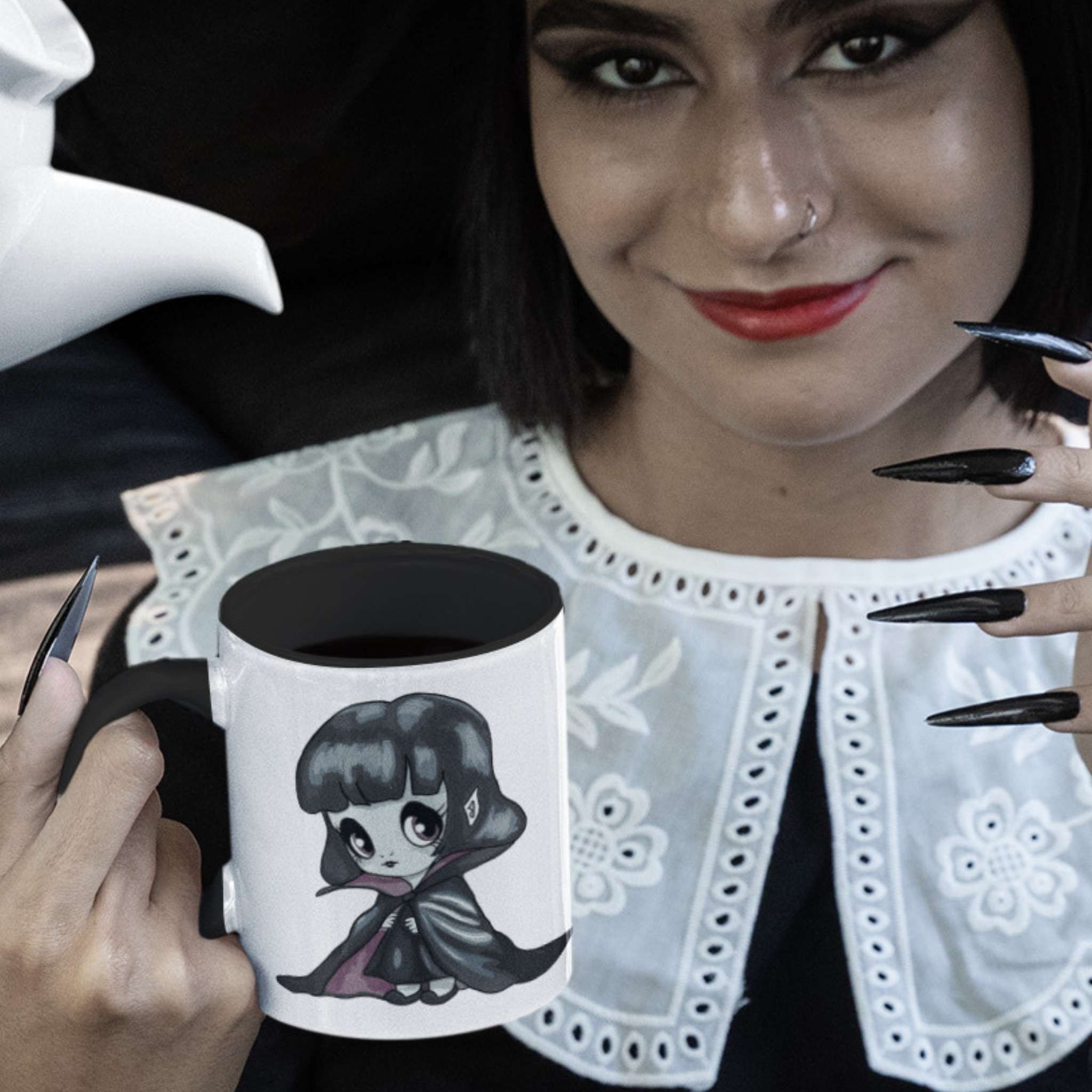 Woman with red lips and black nails holding the cute vampire coffee mug filled with black coffee