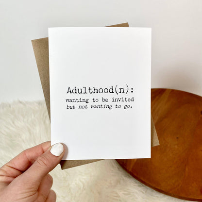 A hand holds a white greeting card with black printed text reading &