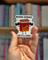 Sticker with a cartoon book character and text &
