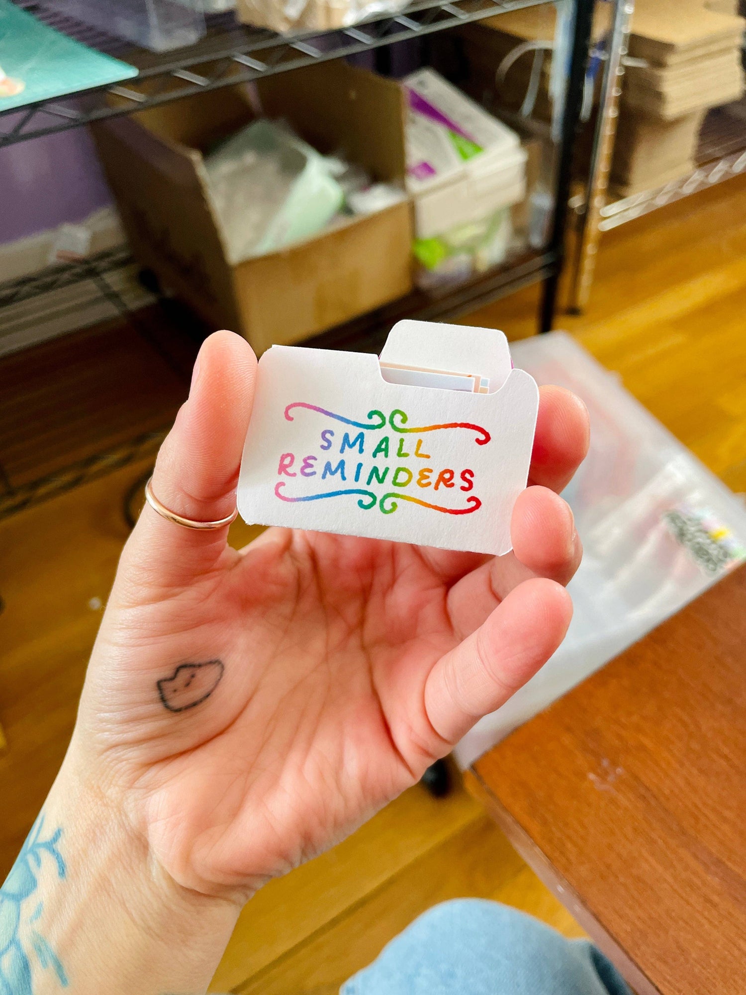 Hand holding a small white card with colorful text &
