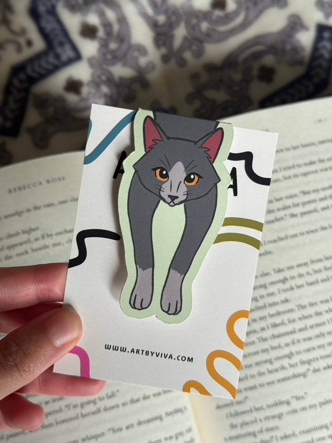 Sticker of a cat held over a book with &