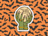 A die-cut sticker featuring two green skeletal hands holding a glowing moon with the text &