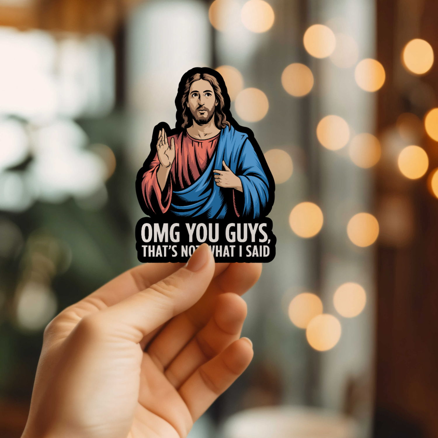 Sticker of a religious figure with text held by a hand against a blurred bokeh background