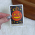 A hand with silver nail polish holds a tarot card featuring &