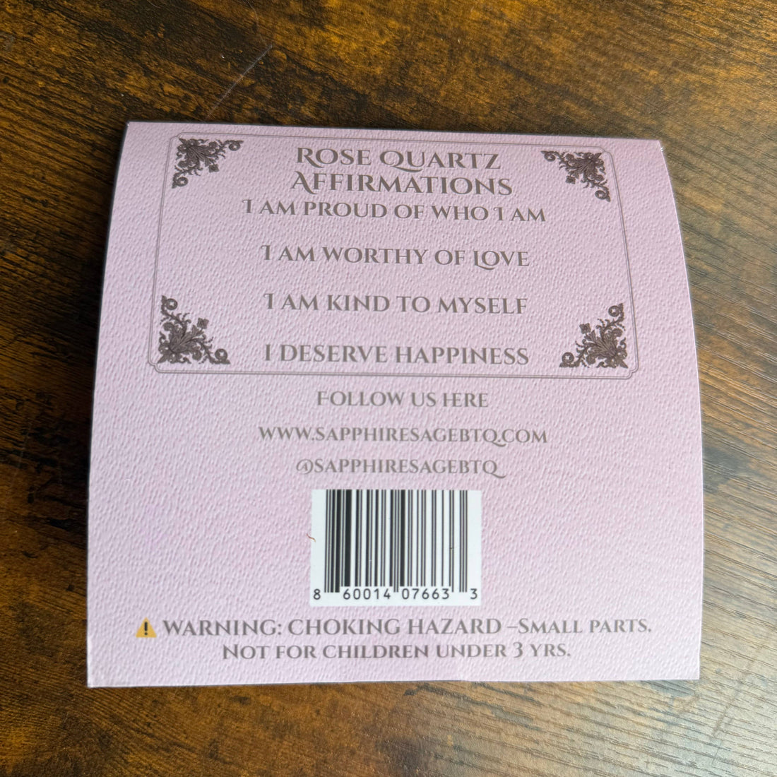 Pink card with affirmations on a wooden surface