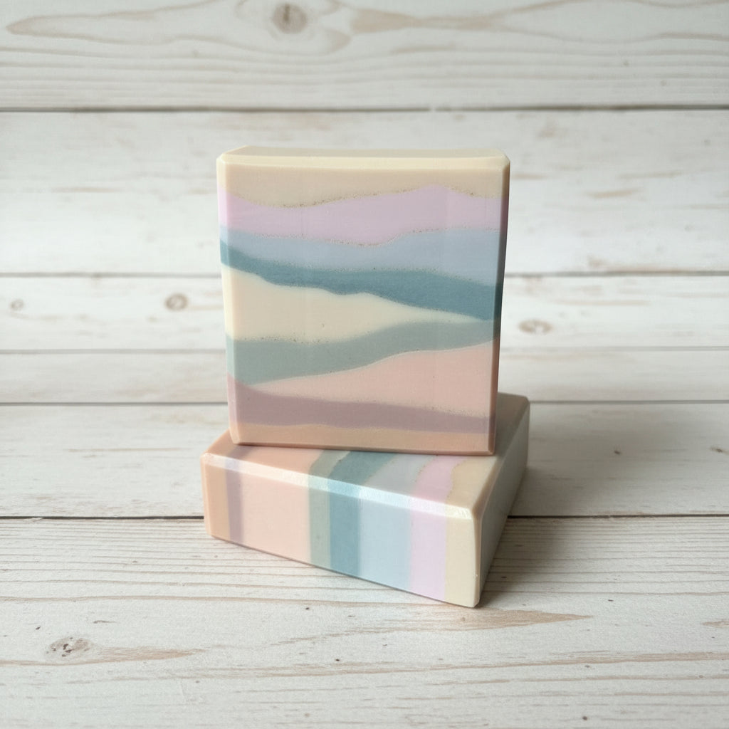 Two soap bars with a pastel color pattern on a wooden surface