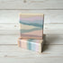 Two soap bars with a pastel color pattern on a wooden surface