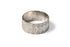 A textured sterling silver cigar band ring with a handstamped diamond design on the edging, made ethically in. mexico of recycled metals, flat lay