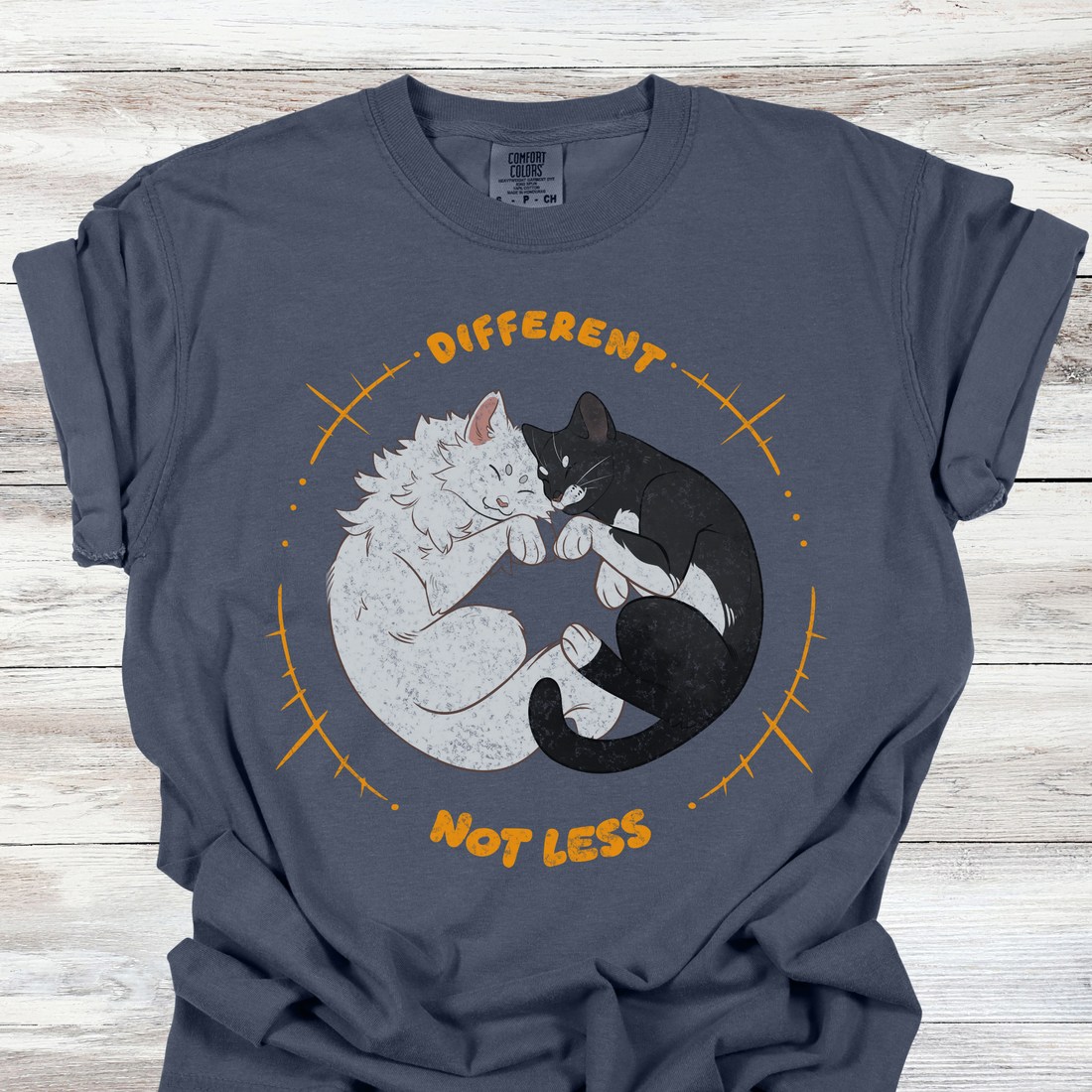 Neurodiversity acceptance graphic tee showing a white cat and black cat sleeping in a circle with the phrase Different Not Less