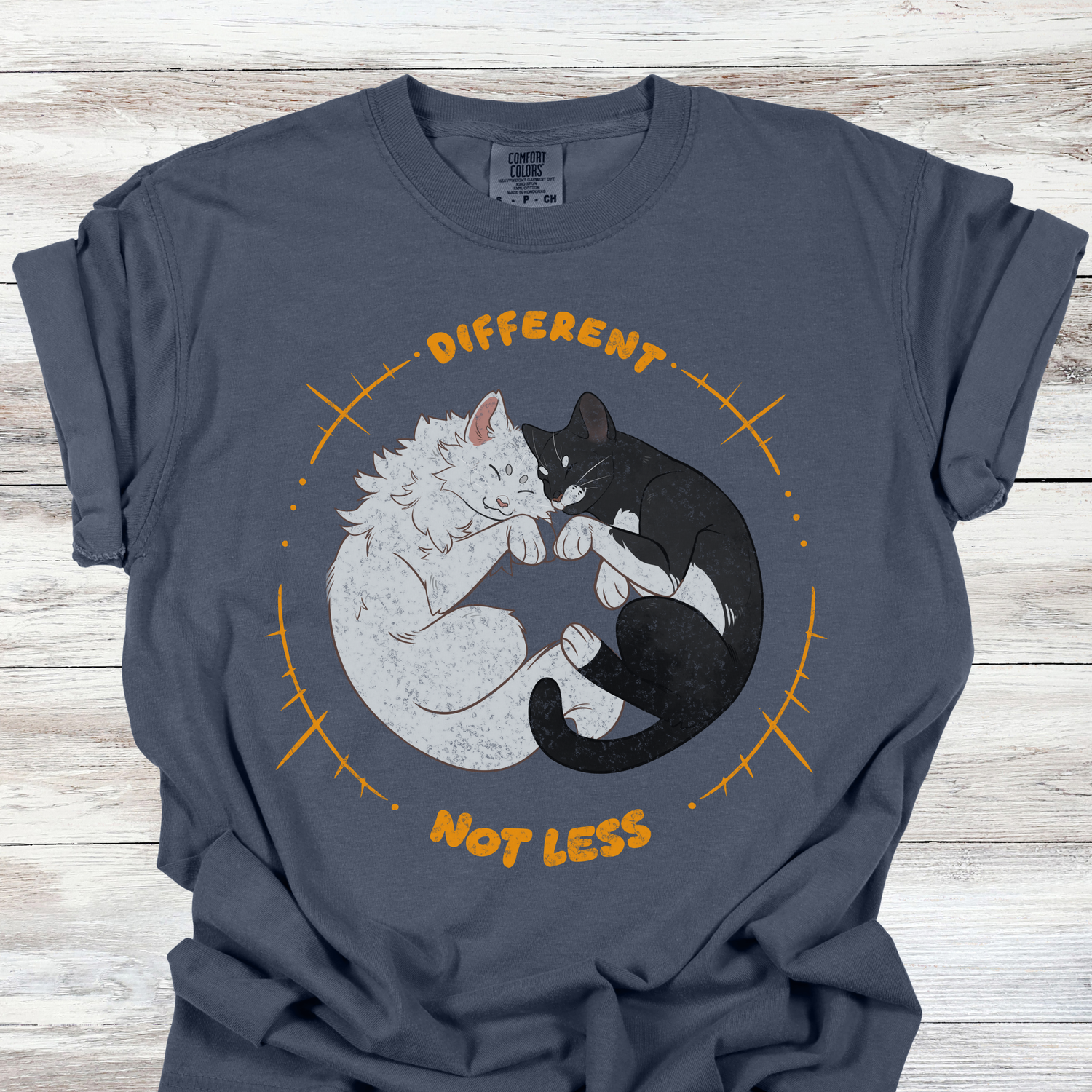 Neurodiversity acceptance graphic tee showing a white cat and black cat sleeping in a circle with the phrase Different Not Less