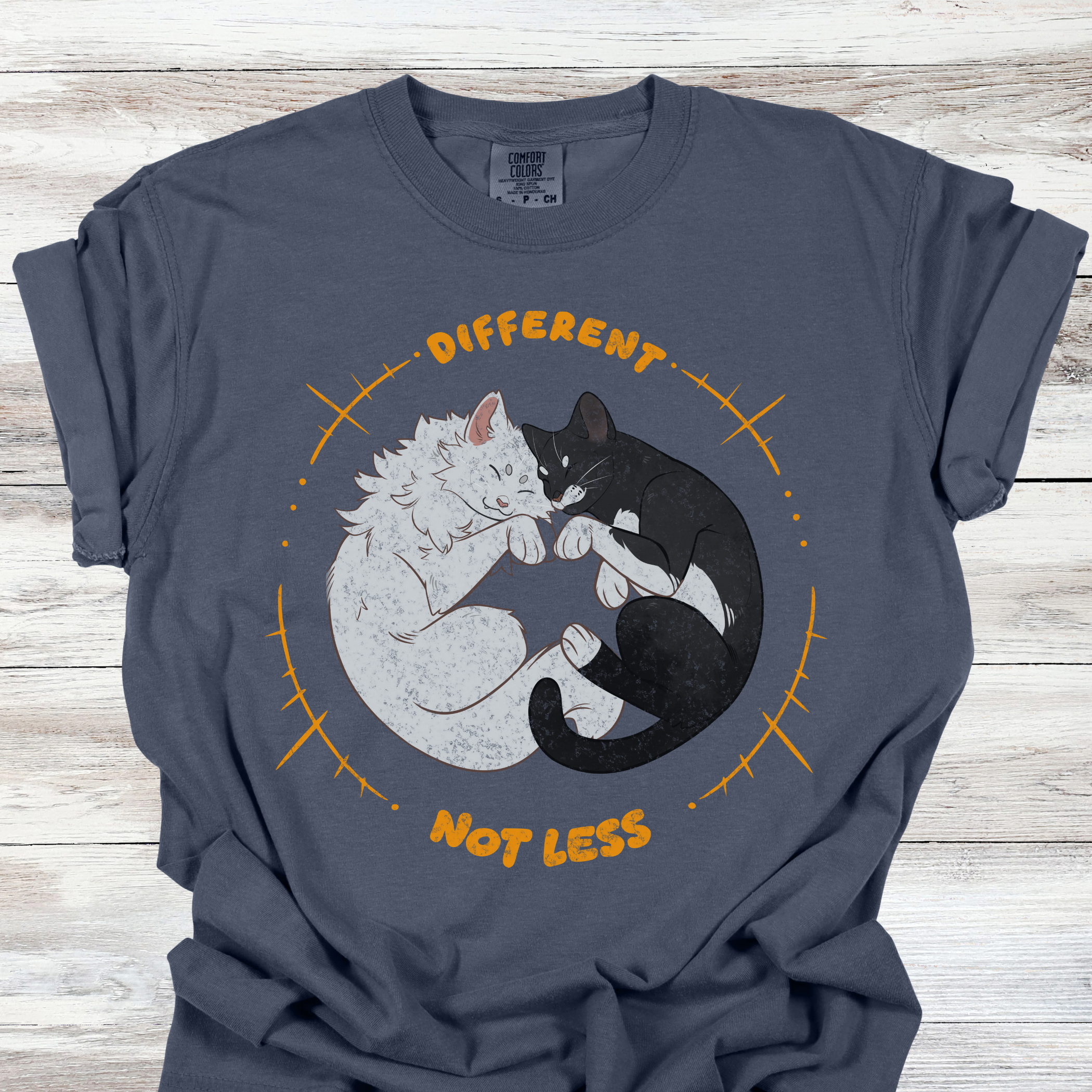 Neurodiversity acceptance graphic tee showing a white cat and black cat sleeping in a circle with the phrase Different Not Less