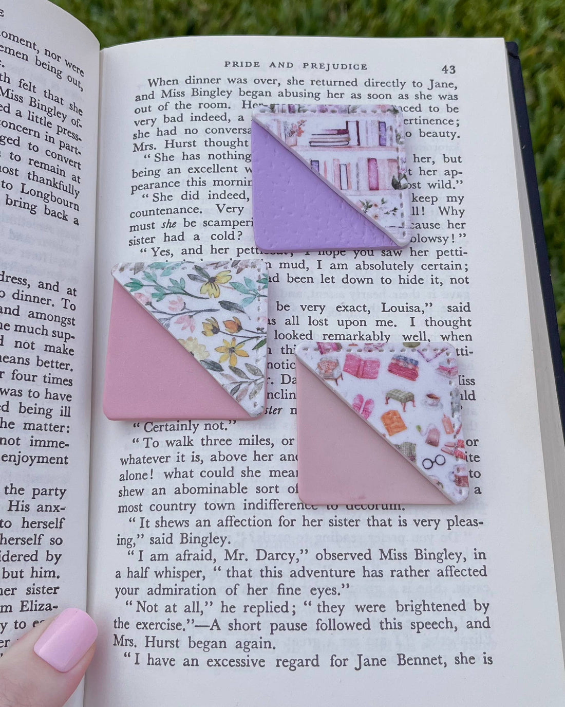 Decorative corner bookmarks on an open book with a blurred green outdoor background