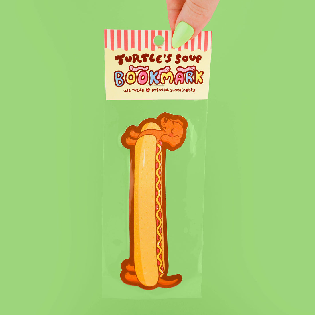 Bookmark shaped like a hot dog with a cartoon face on a green background