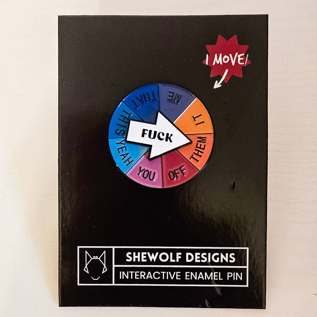 Interactive enamel pin with colorful wheel and text on a black card, branded &