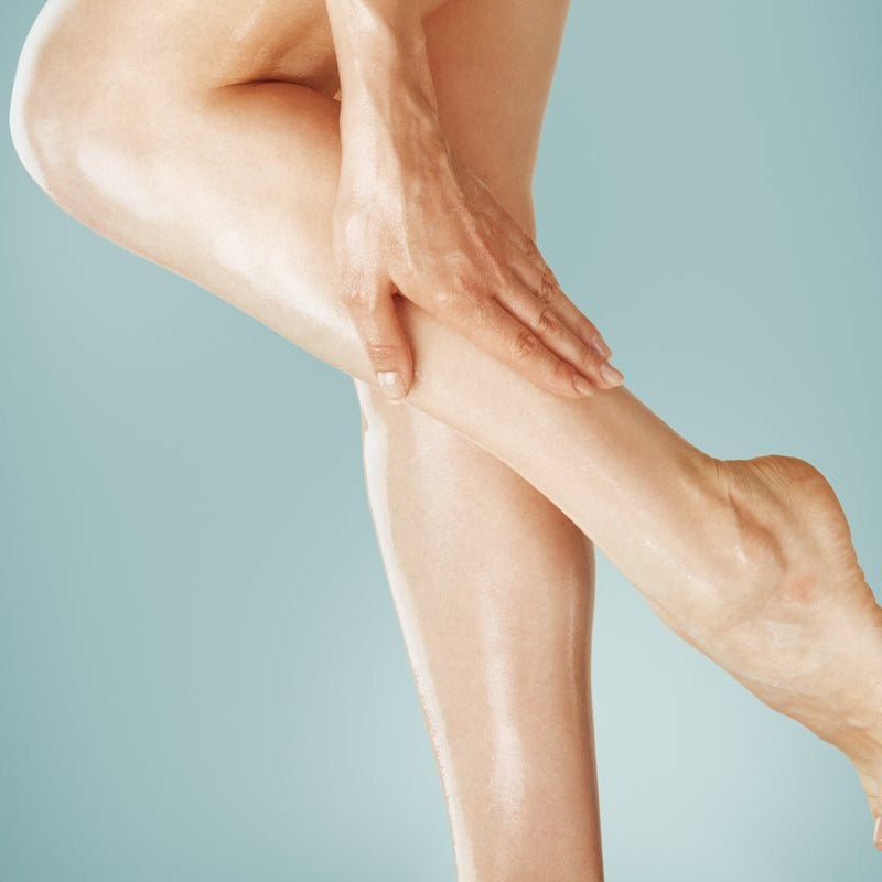 Woman rubbing Elixir Mind Body Botanicals Massage + Body Oils into her legs available at Elixir Mind Body Boutique