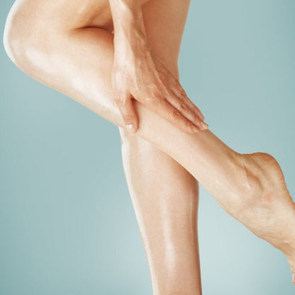 Woman rubbing Elixir Mind Body Botanicals Massage + Body Oils into her legs available at Elixir Mind Body Boutique