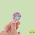 Hand holding a round sticker with &