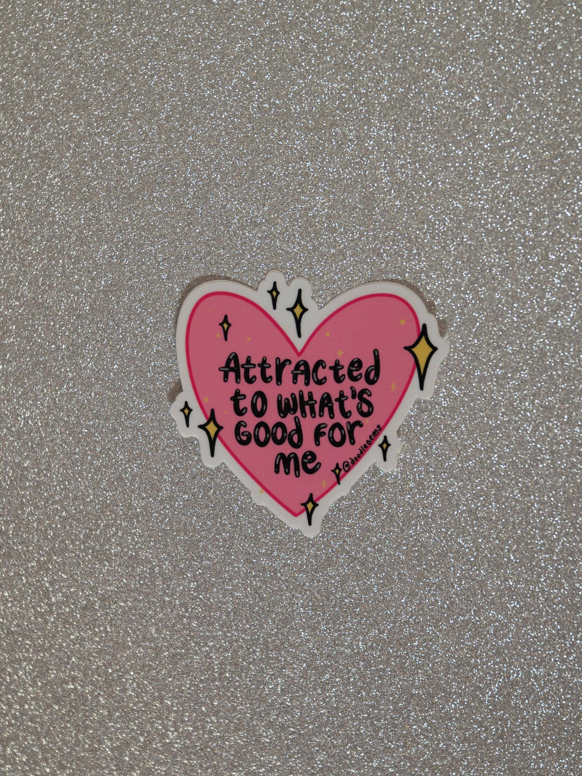Pink heart-shaped sticker with text on a glittery gray background