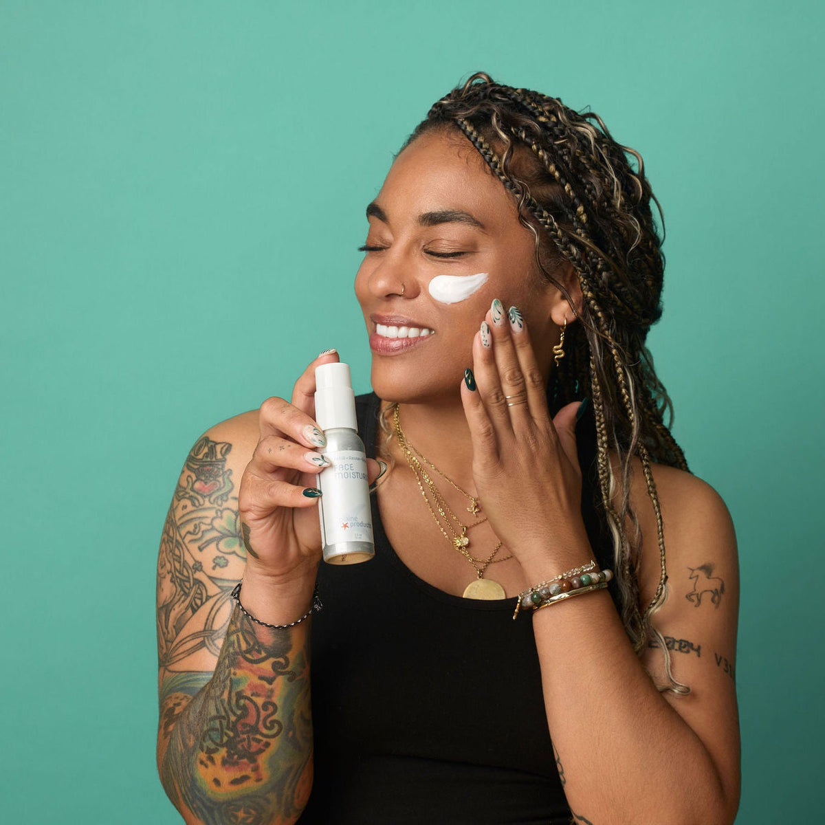 Woman applying plant-based face moisturizer on her face holding an aluminum bottle.