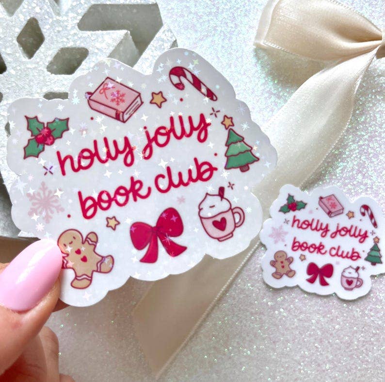 A hand with pink nail polish holds a scalloped white sticker that reads &