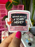 A hand with bright pink nail polish holds a die-cut sticker shaped like a pink retro television. The screen of the TV is black with the white text &