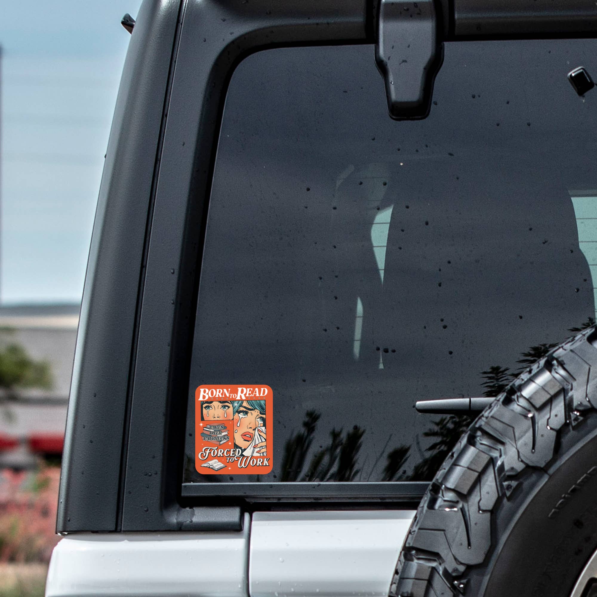 Car window with a sticker and tire visible outdoors