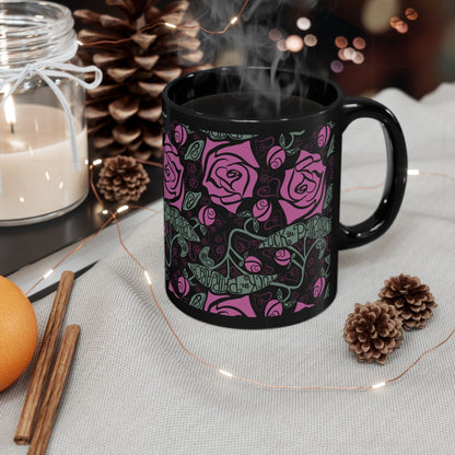 Steaming black ceramic feminist mug with fuchsia rose wrap-print surrounded by pine cones, cinnamon sticks, and candles — cozy holiday gift scene