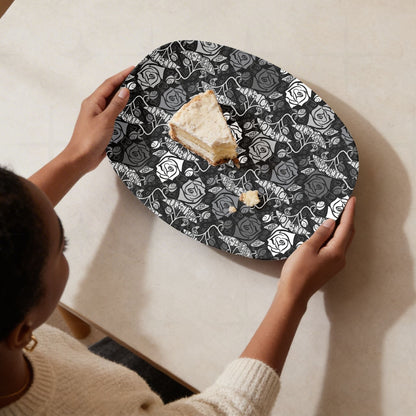 Overhead view of feminist hidden profanity serving platter with slice of cake showing dark gothic rose pattern with protest banners held from above on cream surface