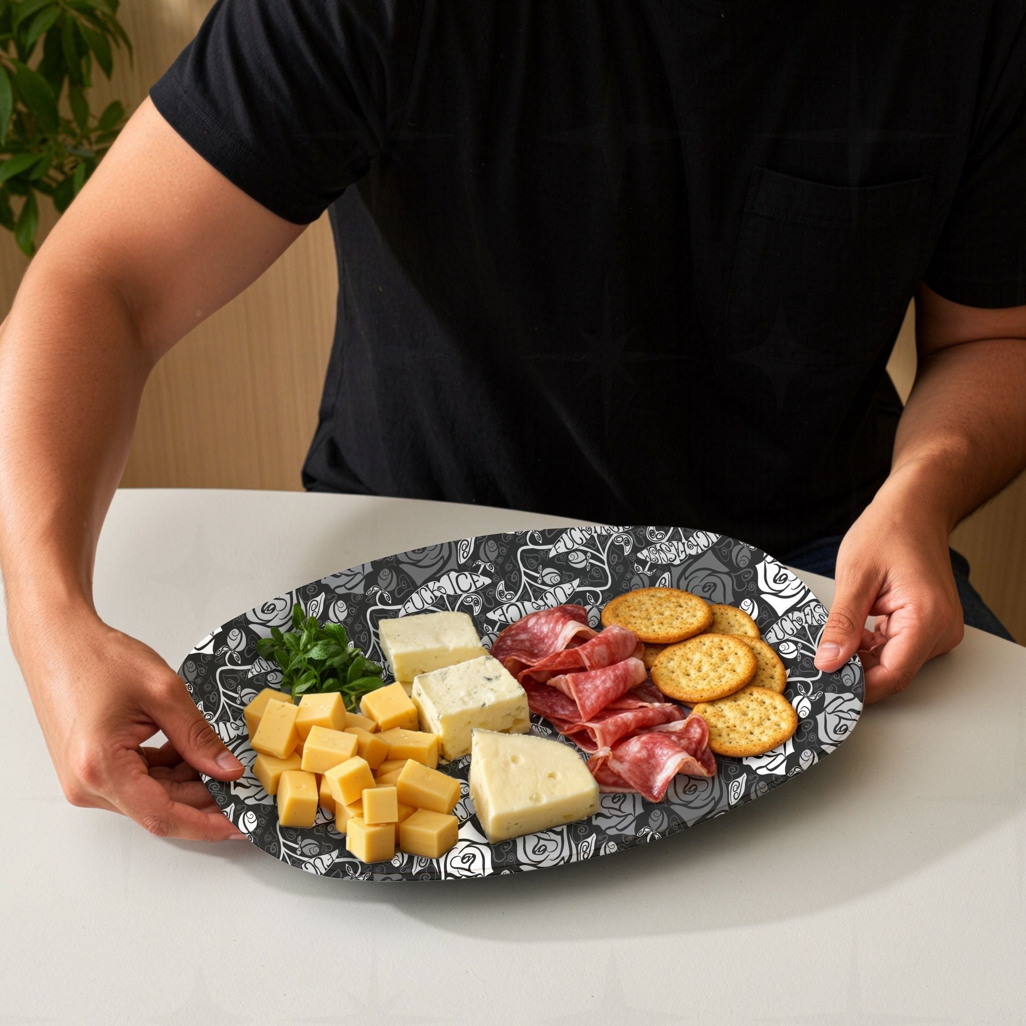 Feminist hidden profanity serving platter loaded with charcuterie spread including cheese salami crackers and herbs showing gothic rose pattern on white table
