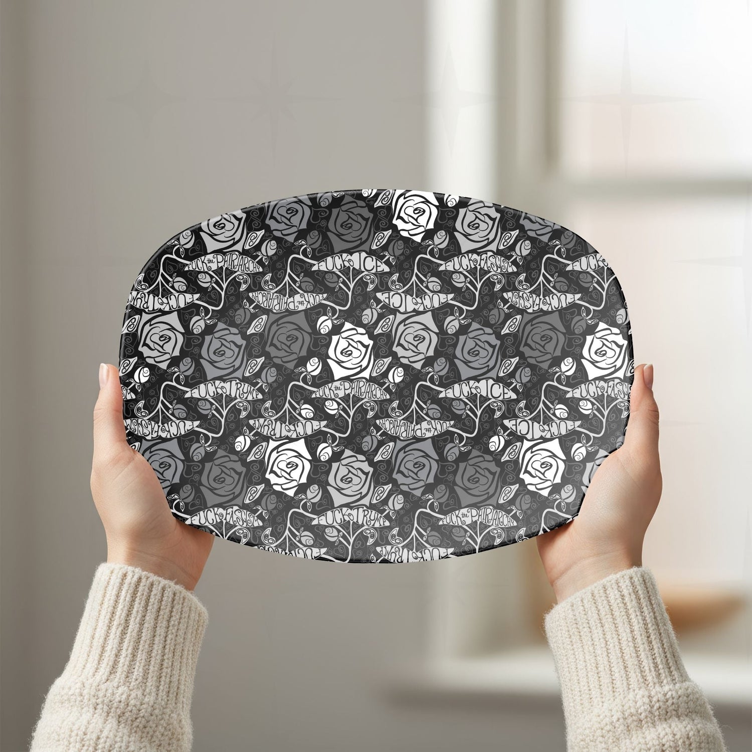 Person in cream sweater holding feminist hidden profanity serving platter showing dark gothic rose repeat pattern in white kitchen