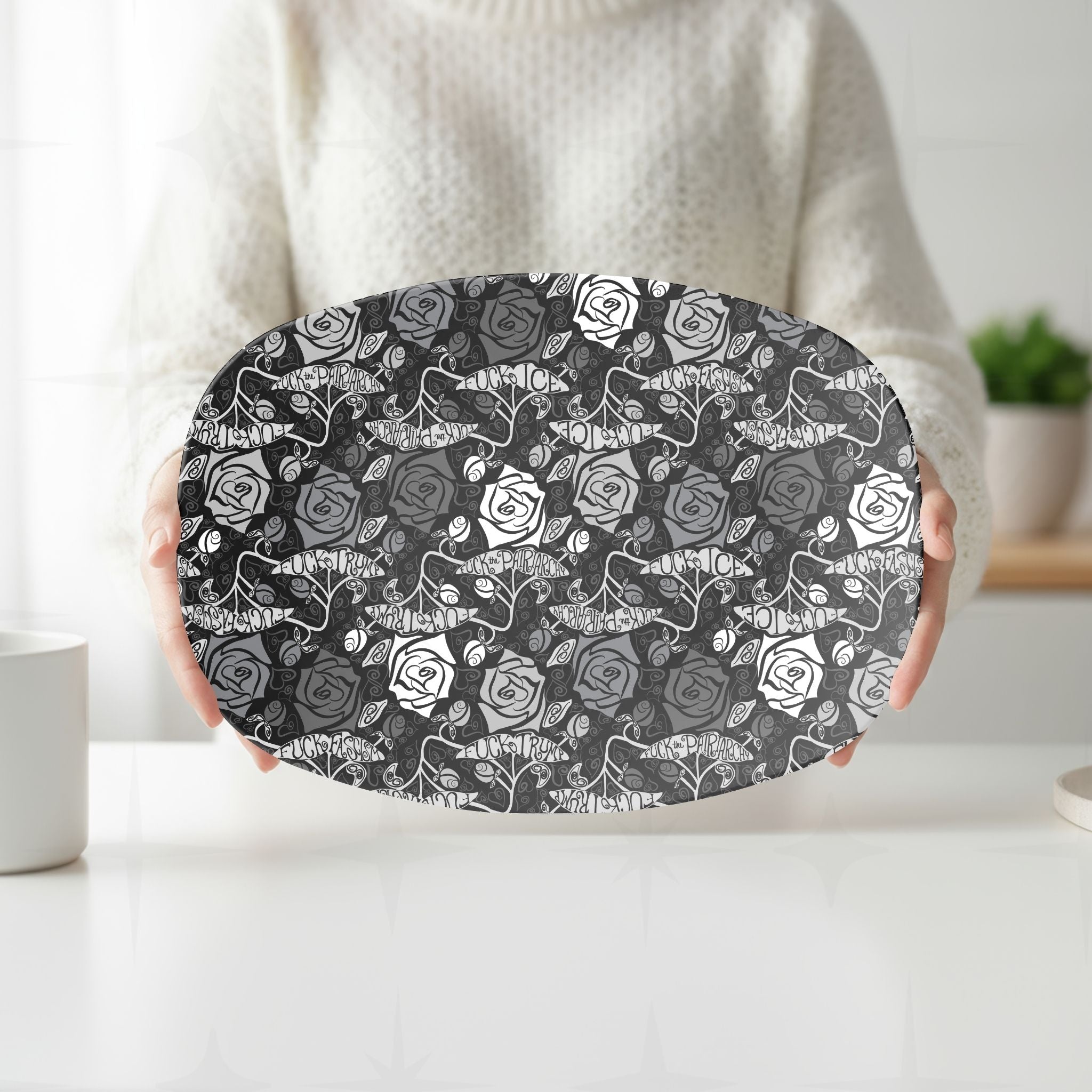 Person in cream sweater holding feminist hidden profanity serving platter showing dark gothic rose repeat pattern in white kitchen