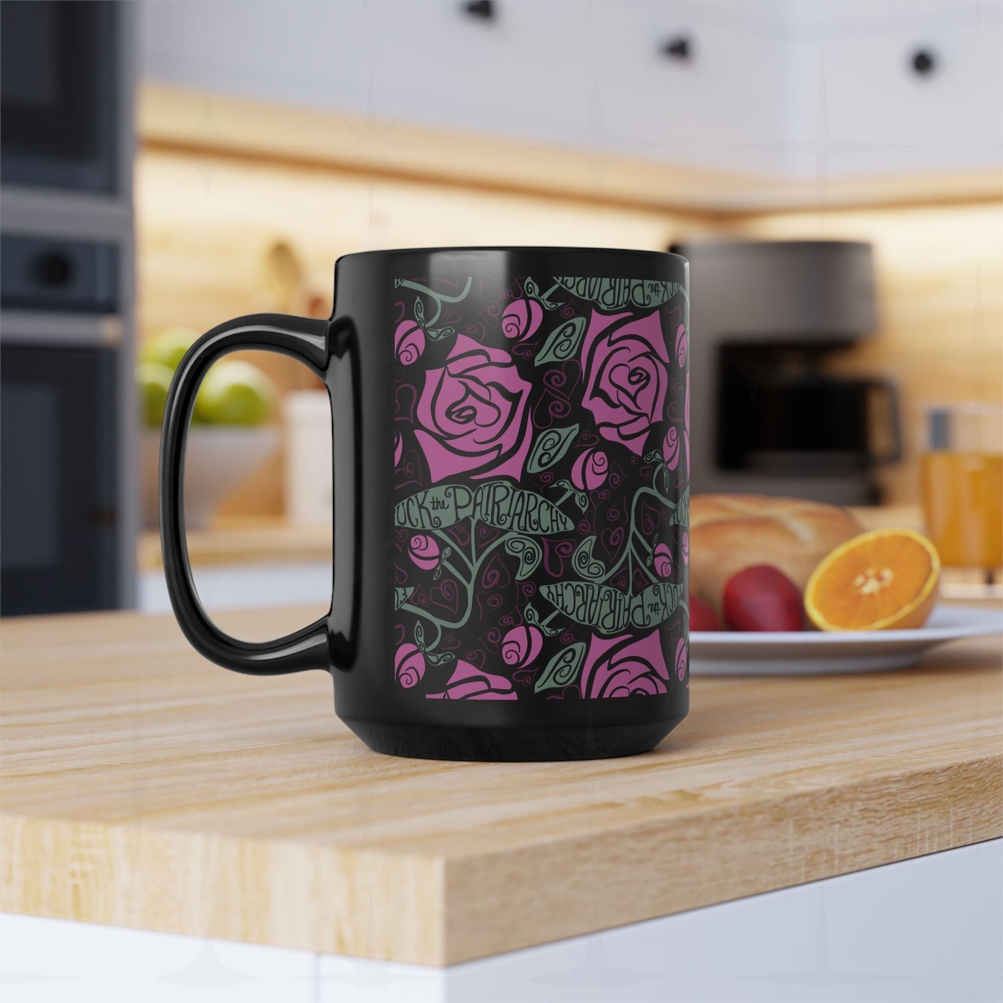15oz black feminist coffee mug with dark floral fuchsia rose and Fuck the Patriarchy pattern on kitchen counter, handle facing left