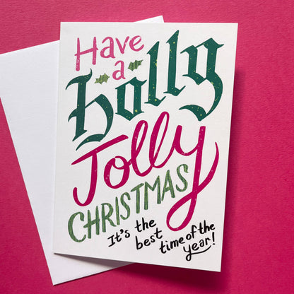 A white Christmas greeting card with festive hand-lettered text reading &