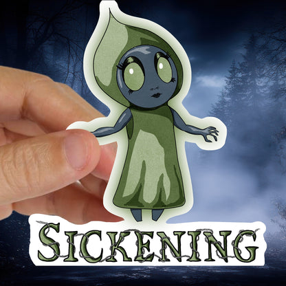 Hand holding the Flatwoods Monster sticker against a foggy blue winter forest background