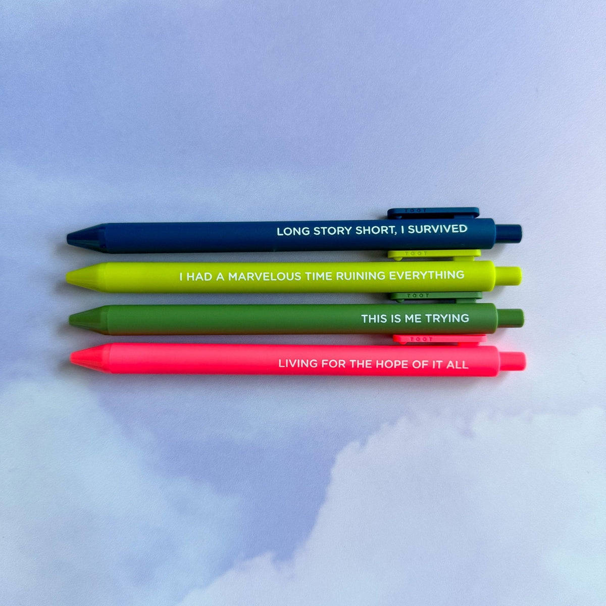 Folkmore Pen Set detail — neon coral and navy jotter pens with embossed lettering by indie artist MangoIllustrated