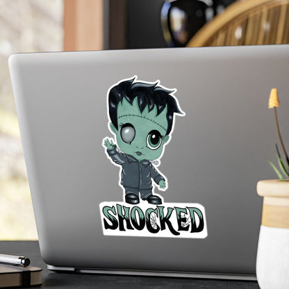 Large chibi Frankenstein sticker with mint-green skin and SHOCKED lettering on the back of a silver laptop