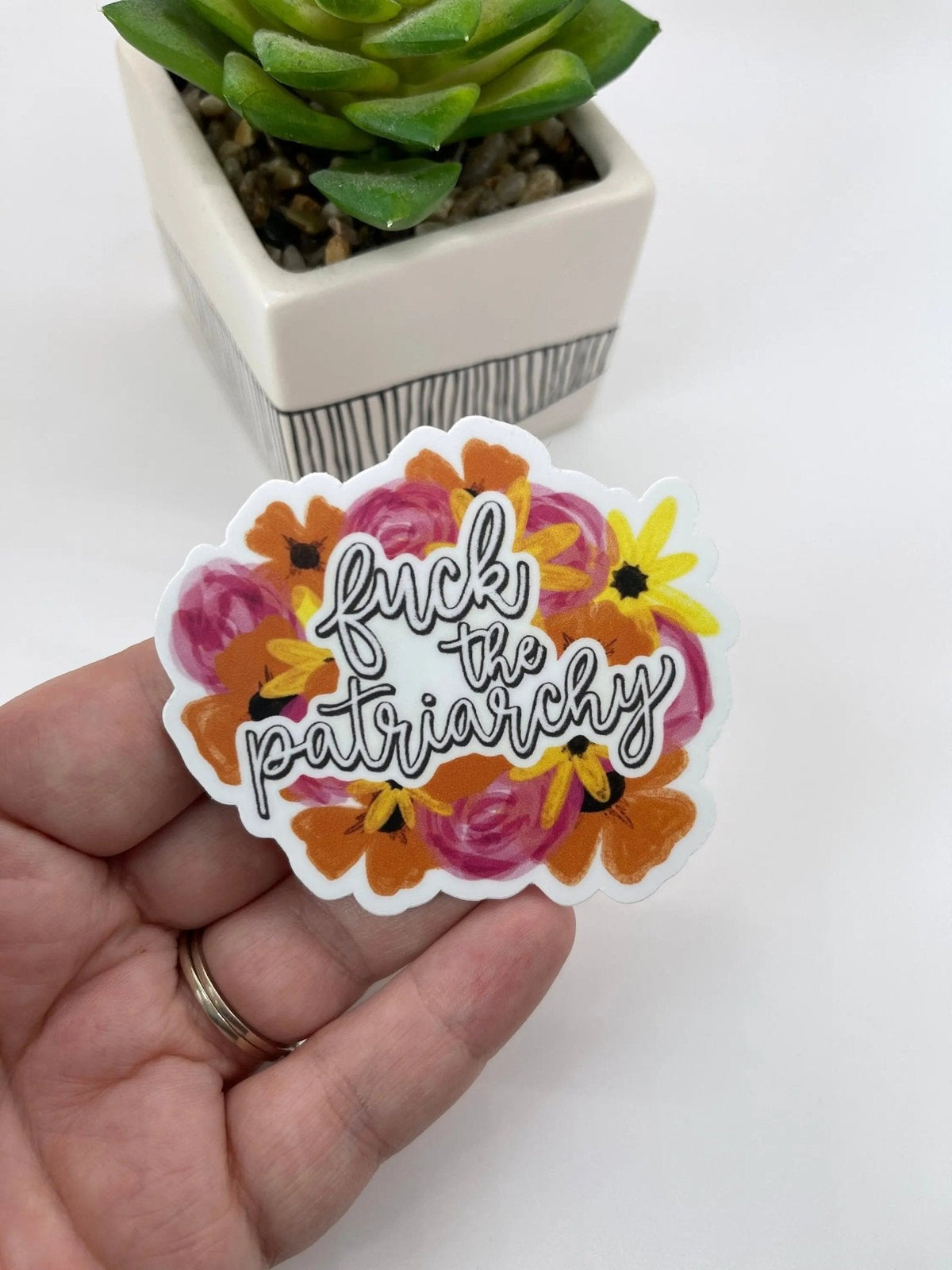 Fuck The Patriarchy Sticker flat lay — red era floral feminist sticker by MangoIllustrated