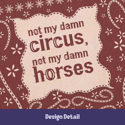 Close-up of hand-lettered text reading not my damn circus not my damn horses on cream cartouche with stitched embroidery border detail on burgundy journal cover