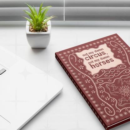 Snarky western journal on white desk next to laptop and small succulent plant showing not my damn circus hand-lettered cover