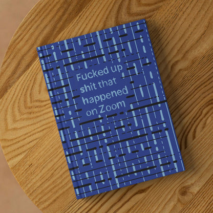 Funny Zoom profanity hardcover journal lying on round wooden surface showing front cover with cobalt blue abstract grid pattern